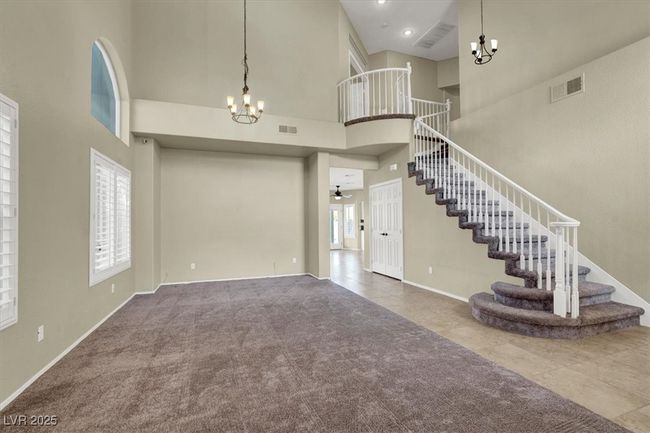 Carpeted foyer with a chandelier, a high ceiling, stairway, and a ceiling fan | Image 7