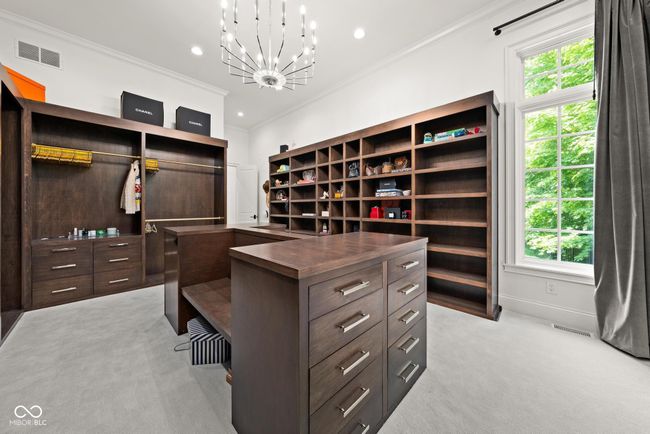 primary closet, walk in closet with light carpet and a chandelier | Image 34