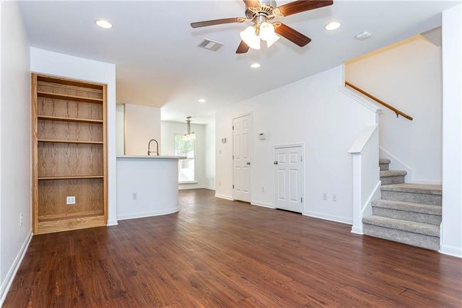 Unfurnished living room featuring stairs, dark wood finished floors, ceiling fan, and recessed lighting | Image 6