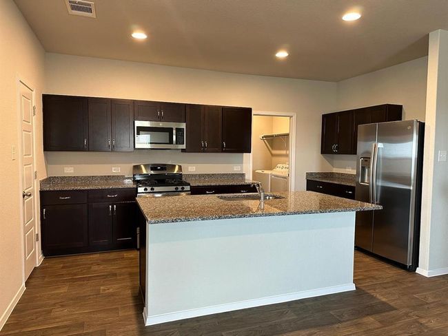 Kitchen featuring stainless steel appliances, washer and clothes dryer, a sink, dark wood-style flooring, and recessed lighting | Image 5