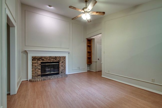 Unfurnished living room featuring light wood-style floors, a ceiling fan, and a fireplace | Image 5