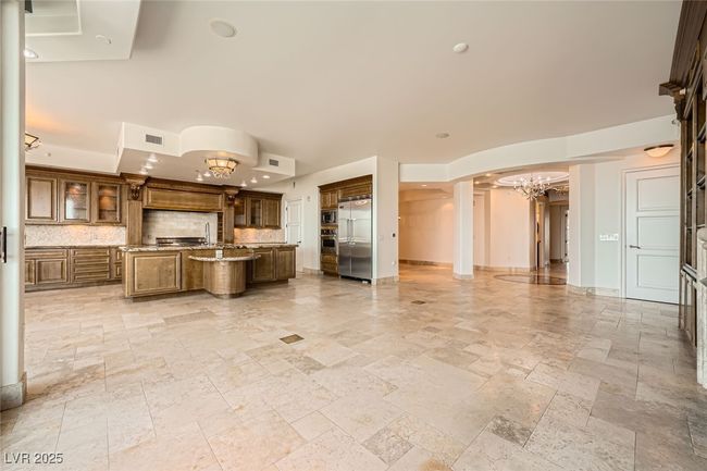 Kitchen featuring a chandelier, built in appliances, a center island with sink, stone tile flooring, and decorative backsplash | Image 9