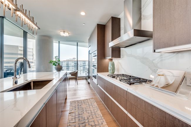 Kitchen featuring wall chimney exhaust hood, appliances with stainless steel finishes, a sink, modern cabinets, and a wall of windows | Image 8
