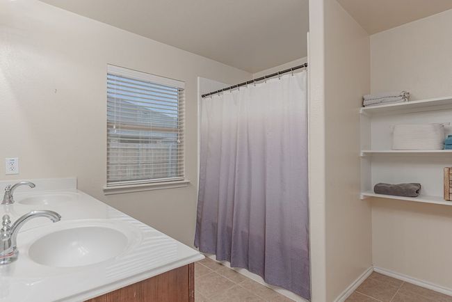 Bathroom featuring double vanity, a sink, tile patterned floors, and a shower with shower curtain | Image 16
