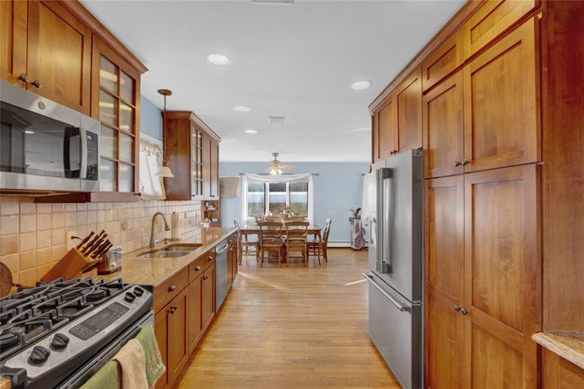 Kitchen with appliances with stainless steel finishes, light stone counters, decorative backsplash, pendant lighting, and sink | Image 16
