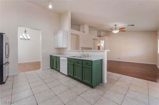 Kitchen with green cabinets, a sink, dishwasher, freestanding refrigerator, and light countertops | Image 15