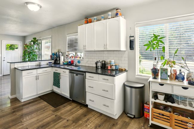 Kitchen with stainless steel dishwasher, dark wood-style floors, a peninsula, white cabinets, and tasteful backsplash | Image 7