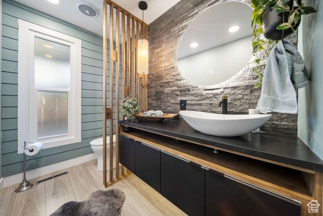 Bathroom featuring toilet, vanity, wood finished floors, and wooden walls | Image 12