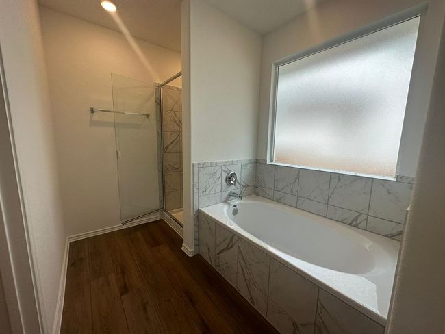 Full bathroom featuring wood finished floors, a stall shower, and a garden tub | Image 30