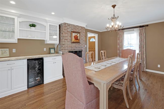 Dining room with crown molding, wine cooler, a chandelier, bar area, and light wood-type flooring | Image 8