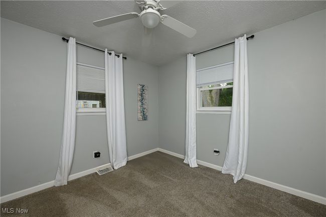 Unfurnished room featuring dark carpet, a ceiling fan, and a textured ceiling | Image 10