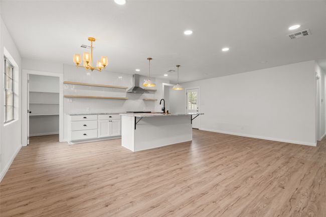 Kitchen with open shelves, wall chimney range hood, recessed lighting, light wood finished floors, and white cabinetry | Image 6
