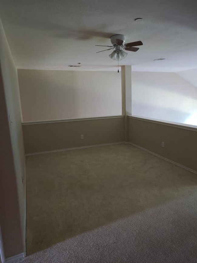 Carpeted empty room featuring ceiling fan, vaulted ceiling, and baseboards | Image 9