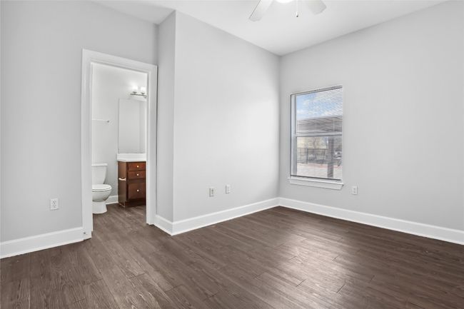 Unfurnished bedroom with baseboards, a ceiling fan, dark wood-style floors, and ensuite bathroom | Image 13