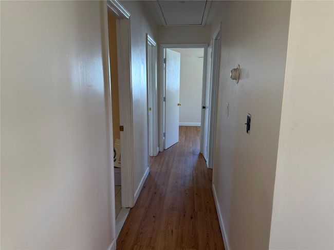Hallway with attic access, wood finished floors, and baseboards | Image 6