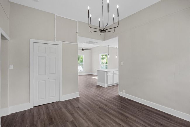 Unfurnished dining area featuring a chandelier, dark wood-type flooring, and a towering ceiling | Image 15