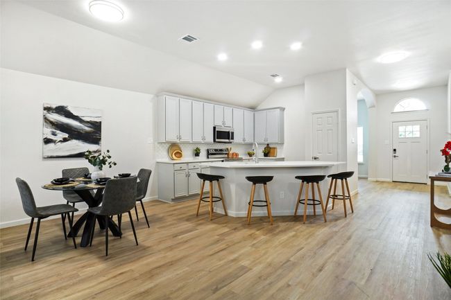 Kitchen featuring appliances with stainless steel finishes, a kitchen bar, a center island with sink, light countertops, and light wood finished floors | Image 9