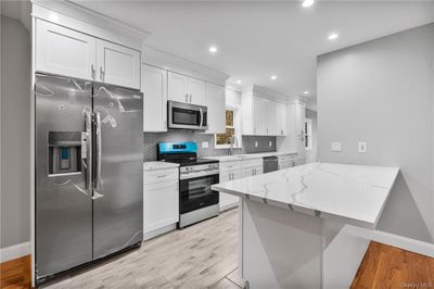 Kitchen featuring appliances with stainless steel finishes, white cabinets, and light hardwood / wood-style floors | Image 1