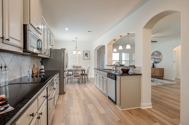 Kitchen featuring appliances with stainless steel finishes, dark countertops, light wood-style flooring, and recessed lighting | Image 7