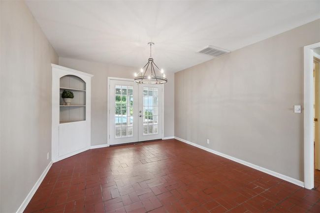 Unfurnished room with a chandelier, brick floors, and french doors | Image 15