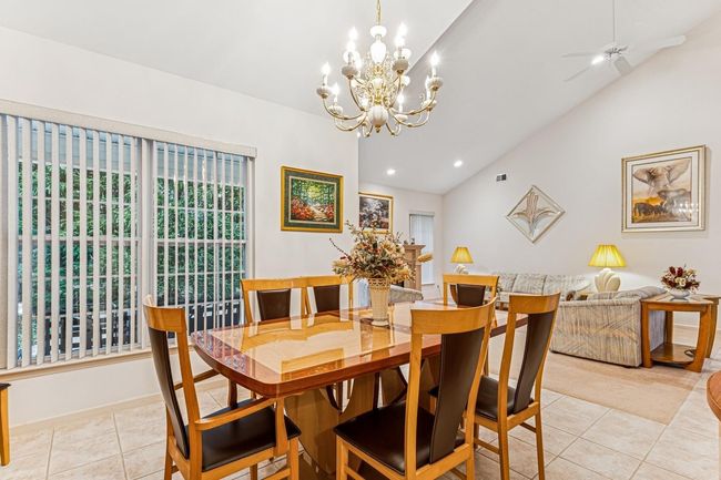 Dining area with light tile patterned flooring, lofted ceiling, recessed lighting, and ceiling fan with notable chandelier | Image 27