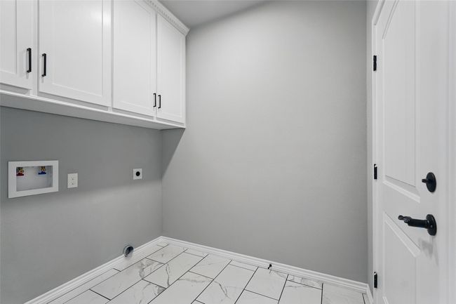 Washroom with tile finish floor, hookup for an electric dryer, baseboards, cabinet space, and washer hookup | Image 24
