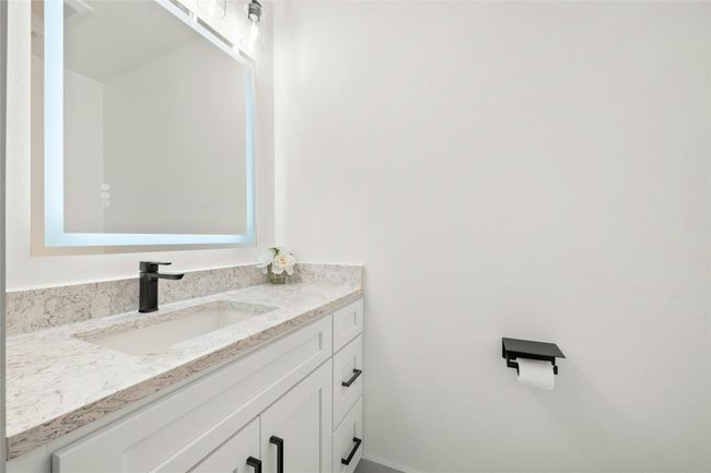 The guest bathroom is located downstairs next to the laundry room. Notice the modern vanity with a quartz countertop, LED mirror, 5inch cabinet pulls and modern black faucet. | Image 15
