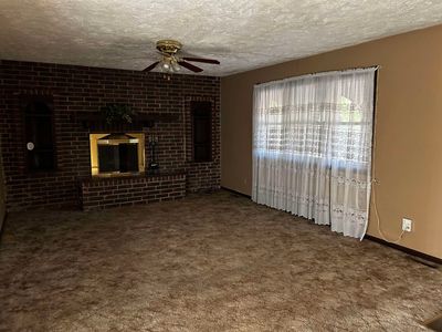 Unfurnished living room with a textured ceiling, carpet flooring, and ceiling fan | Image 2