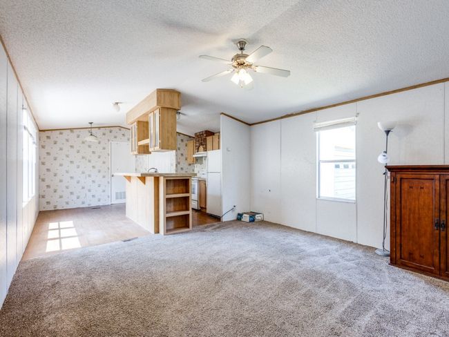 The interior of the mobile home--this shows the living room, dining area, and kitchen. Primary bedroom and laundry room are past the kitchen in this photo. | Image 29