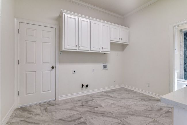 Laundry room with gas dryer hookup, hookup for an electric dryer, washer hookup, light marble finish flooring, and baseboards | Image 24