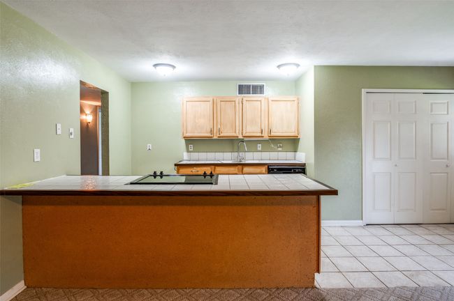 Kitchen with tile counters, cooktop, light brown cabinetry, and a peninsula | Image 10