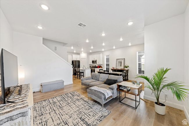 Living room featuring light wood finished floors, stairs, and recessed lighting | Image 6