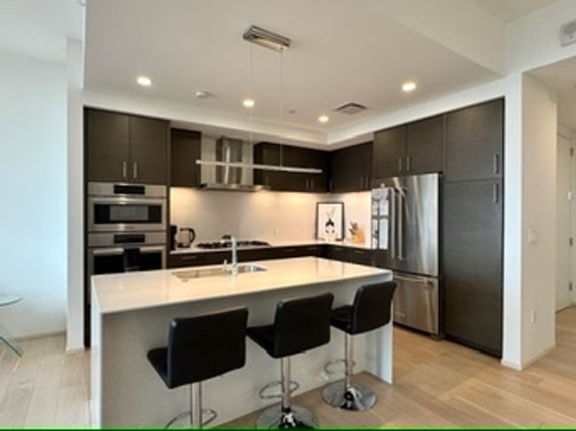 Kitchen with appliances with stainless steel finishes, exhaust hood, a sink, a kitchen bar, and recessed lighting | Image 12