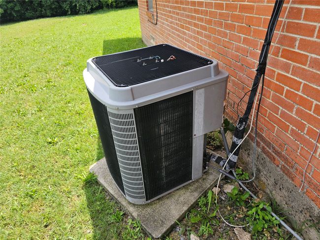 Exterior view of a central air condition unit and brick siding | Image 10
