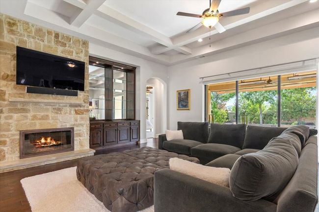 Living room featuring a ceiling fan, arched walkways, beamed ceiling, wood-type flooring, and coffered ceiling | Image 9