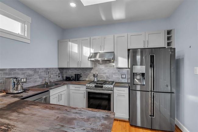 Modern garage apartment kitchen with stainless steel appliances, sleek gray cabinetry, and a stylish brick-style backsplash. Enjoy ample counter space in this contemporary cooking haven. | Image 29