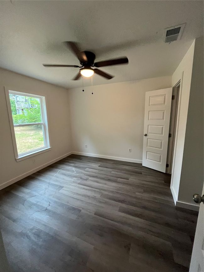 Empty room with ceiling fan, dark wood finished floors, and baseboards | Image 8