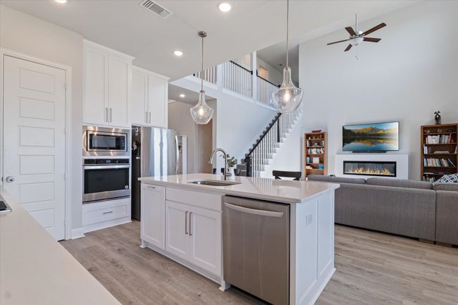 Kitchen with stainless steel appliances, a sink, open floor plan, light wood finished floors, and light countertops | Image 11