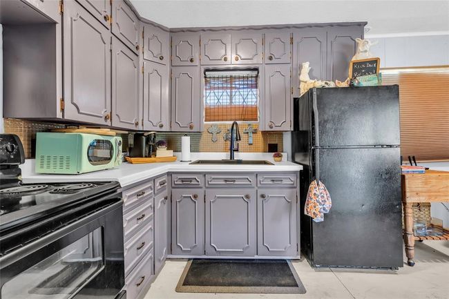 Kitchen featuring black appliances, a sink, gray cabinets, tasteful backsplash, and light countertops | Image 34