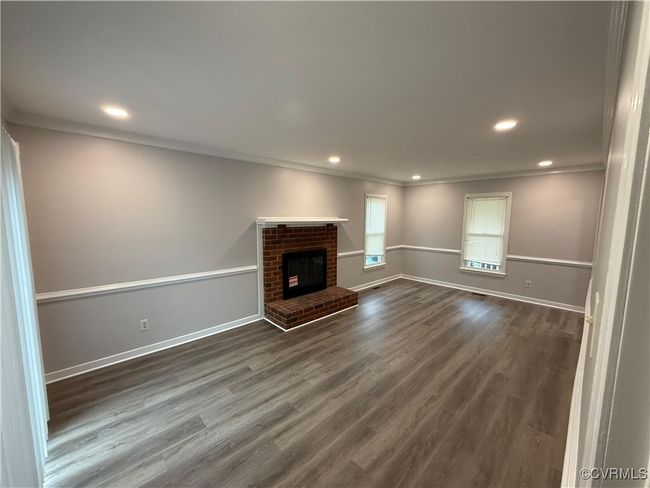 Unfurnished living room with ornamental molding, dark wood-style flooring, recessed lighting, baseboards, and a fireplace | Image 12