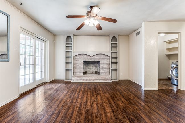 Unfurnished living room with washer / dryer, wood finished floors, a ceiling fan, baseboards, and crown molding | Image 19