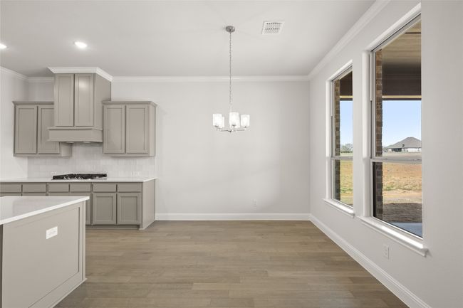Kitchen featuring gray cabinets, stainless steel gas cooktop, a chandelier, crown molding, and tasteful backsplash | Image 5