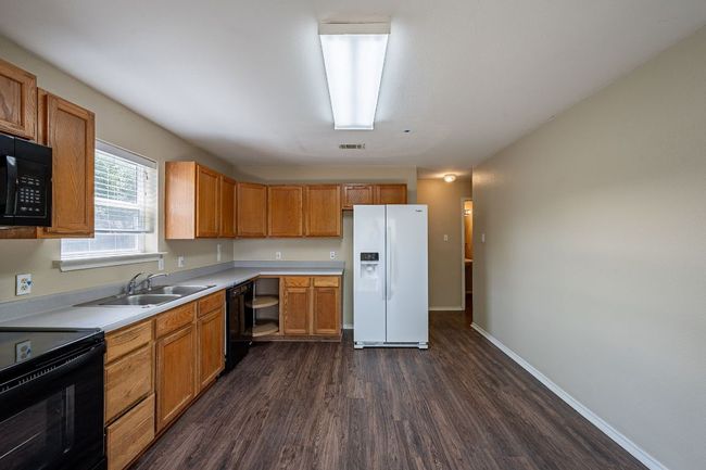 Kitchen featuring black appliances, dark wood-type flooring, a sink, light countertops, and baseboards | Image 10