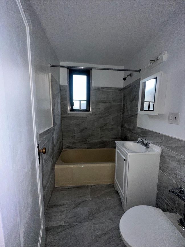 Bathroom with a textured ceiling, tile walls, vanity, and shower / bath combination | Image 17