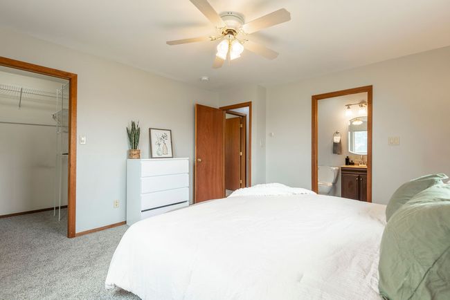 Bedroom with light carpet, a spacious closet, a closet, ensuite bathroom, and ceiling fan | Image 11