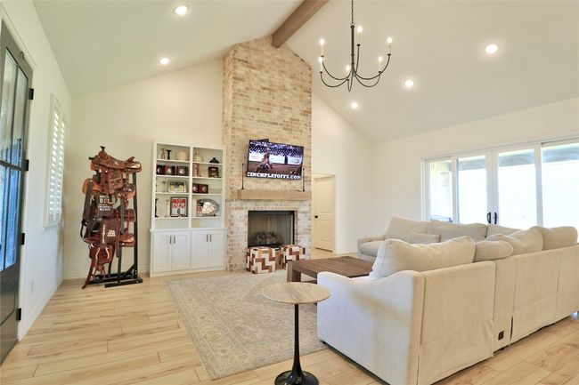 Living room featuring beamed ceiling, light wood finished floors, high vaulted ceiling, and an inviting chandelier | Image 6