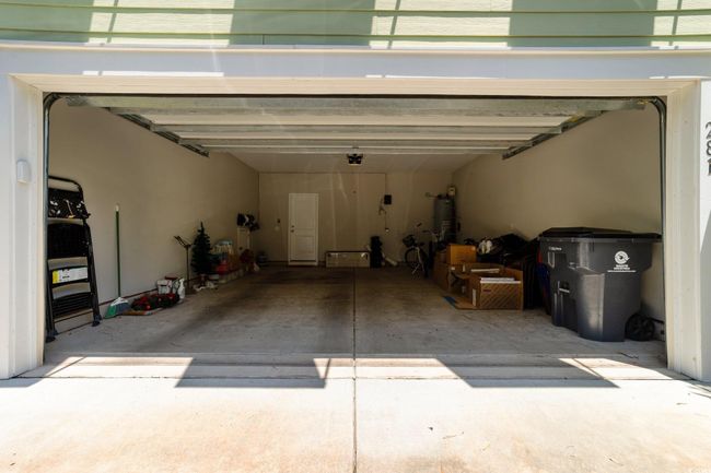 Garage featuring strapped water heater and a garage door opener | Image 32