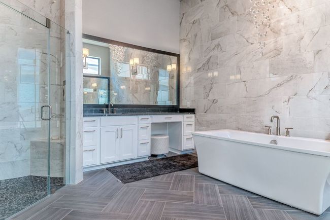 Full bathroom featuring a freestanding tub, vanity, an inviting chandelier, a shower stall, and tile walls | Image 17