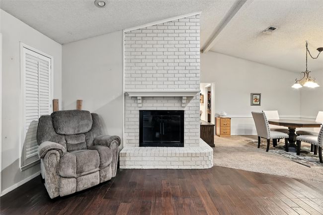 Living room featuring a textured ceiling, dark wood finished floors, and a brick fireplace | Image 12