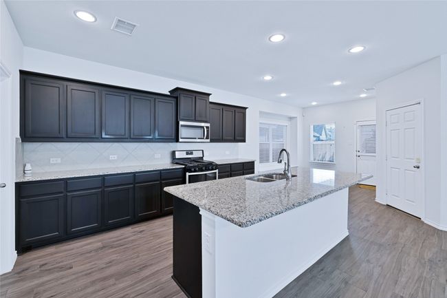 Kitchen with stainless steel appliances, light wood-style flooring, light stone counters, decorative backsplash, and recessed lighting | Image 8